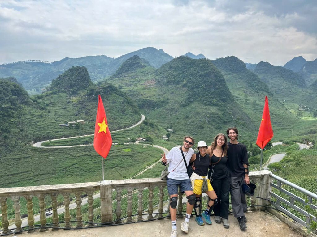 Mr. Biu guests with Vietnamese flags at a mountain viewpoint in Ha Giang