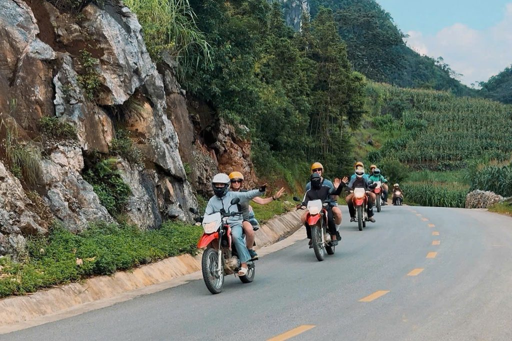 Mr. Biu riders in a line on a quiet valley road in Ha Giang