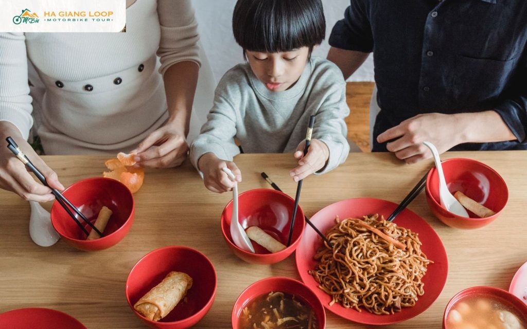 Family sharing noodles and spring rolls around a dinner table