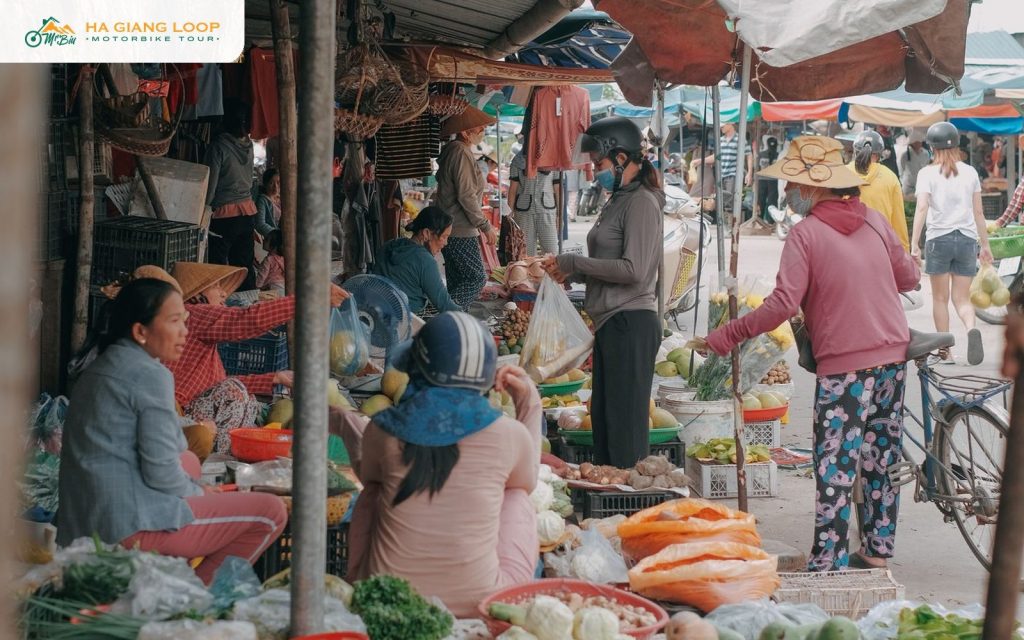 Vendors and shoppers among fresh produce stalls at a morning market