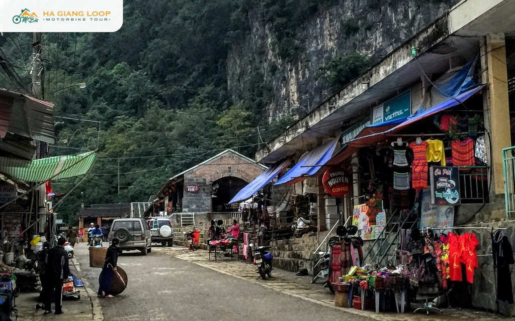 Two SUVs parked beside the old market and souvenir stalls in Dong Van town