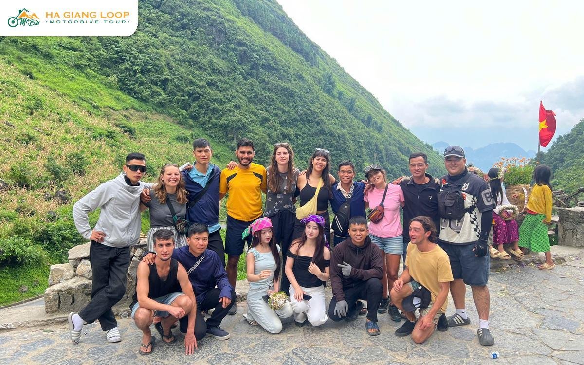Mr. Biu tour group posing at a mountain viewpoint on the Ha Giang Loop