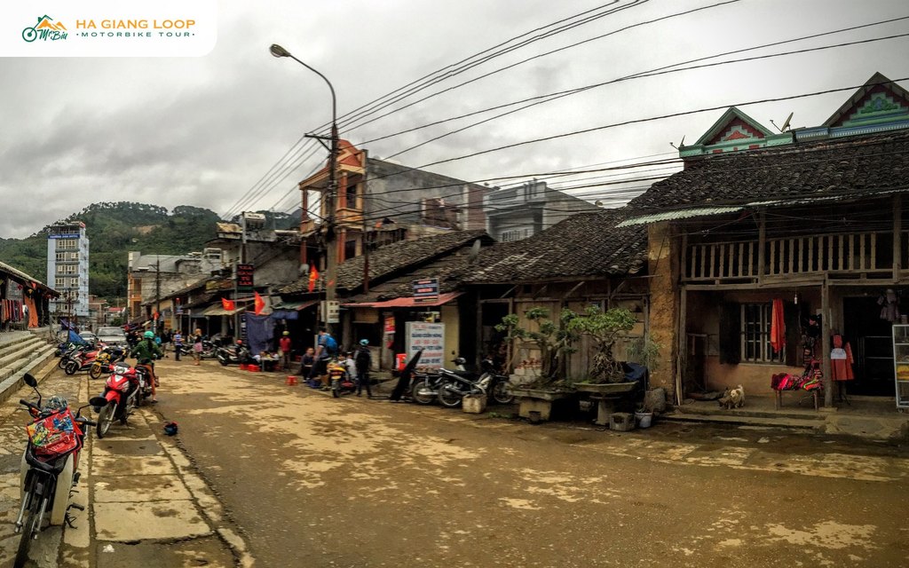 Old tiled-roof houses and parked motorbikes along the street in Dong Van old quarter