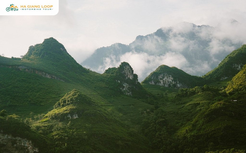 Green limestone peaks around Du Gia with morning cloud behind them