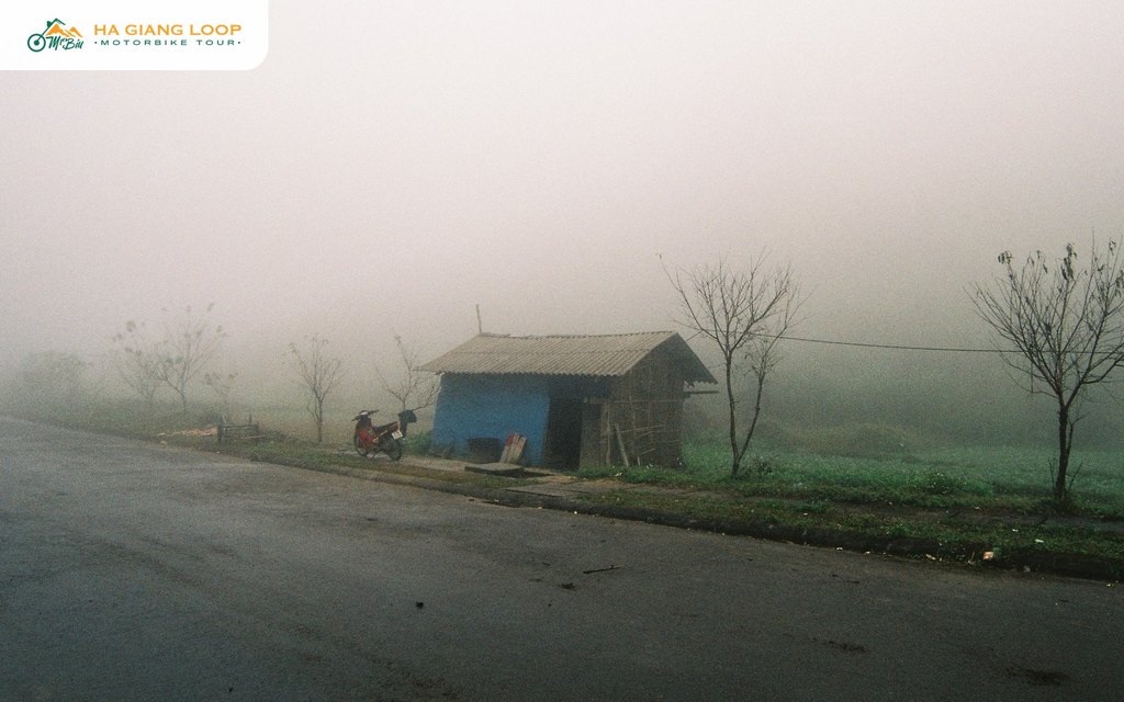 Motorbike parked safely off the road beside a hut in foggy Quan Ba