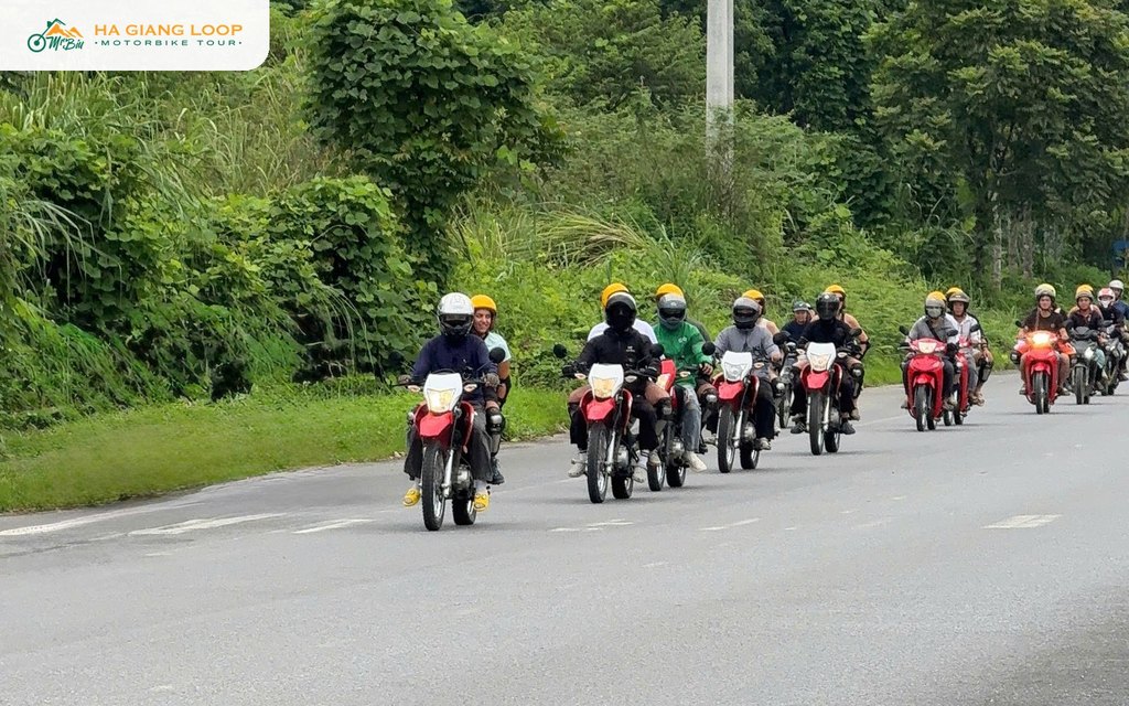 Mr. Biu group riding in convoy with guides on a road in Ha Giang