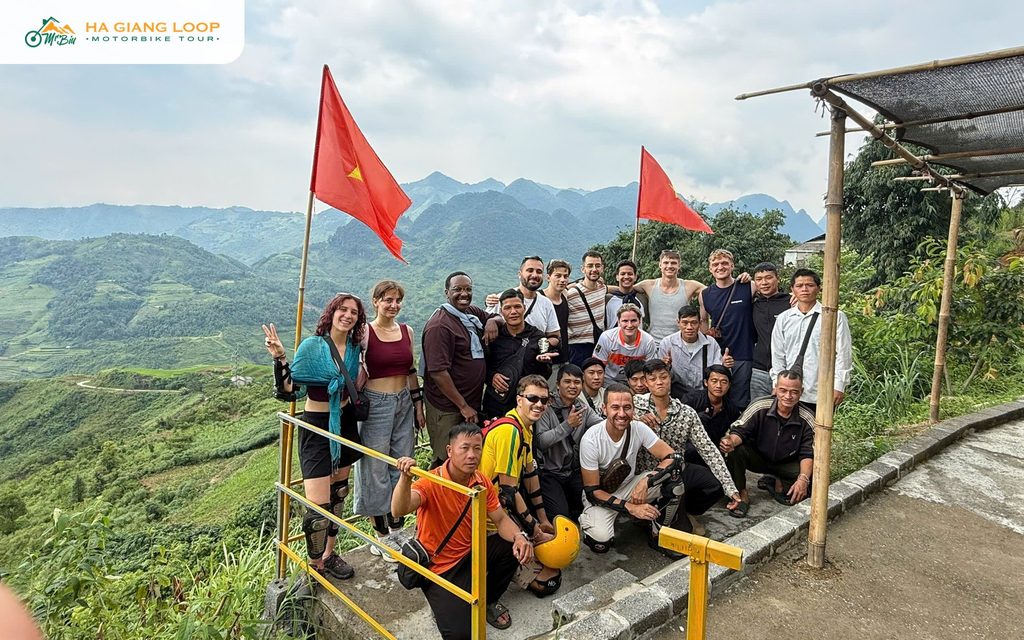 Mr. Biu tour group and guides at a hillside viewpoint with flags