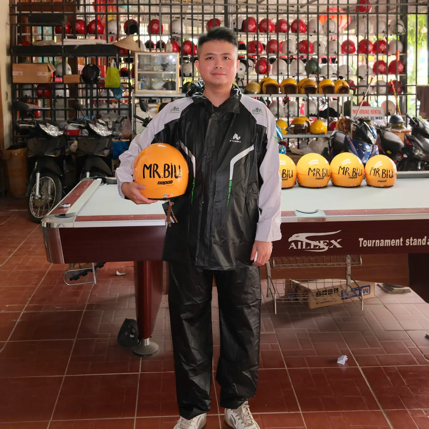 Mr Biu holding a branded helmet at the Ha Giang Loop gear room