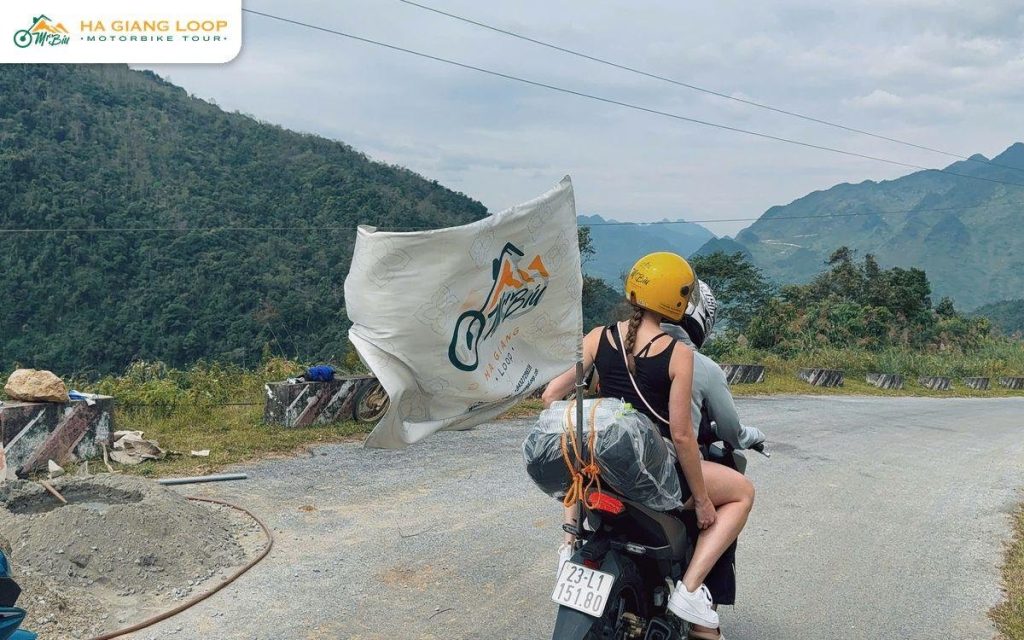 Pillion passenger riding behind a local driver on a mountain road
