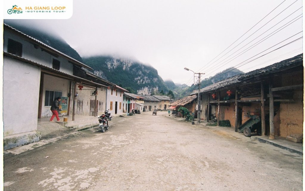 Main street of Pho Bang town with clay houses, lanterns and karst cliffs in fog