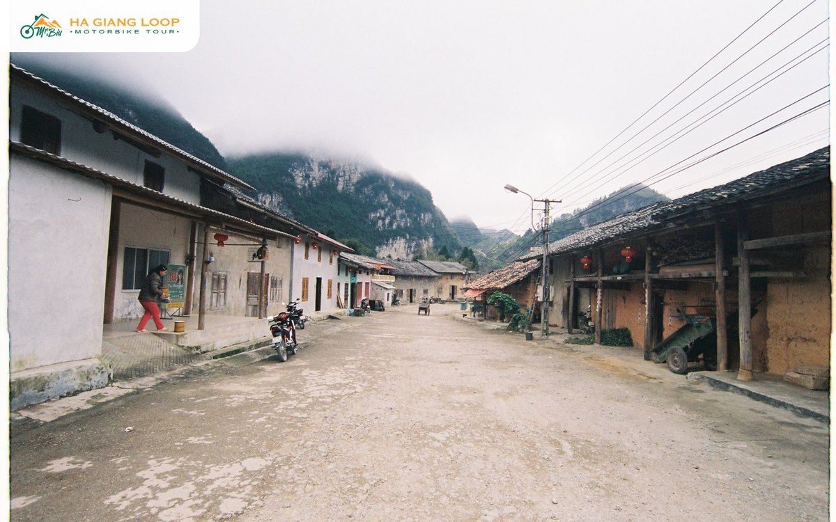 Main street of Pho Bang town with clay houses, lanterns and karst cliffs in fog