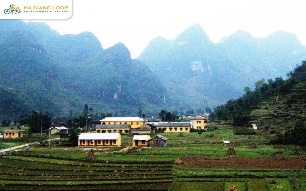Pho Cao commune centre with yellow buildings below karst peaks