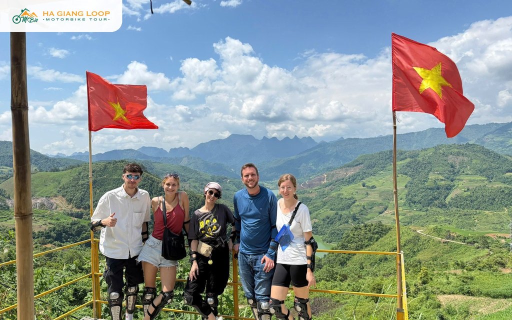 Riders at a viewpoint stop with flags on the Ha Giang Loop
