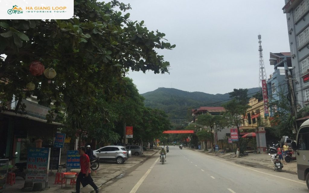 Main street of Yen Minh town with shops, parked motorbikes and hills behind